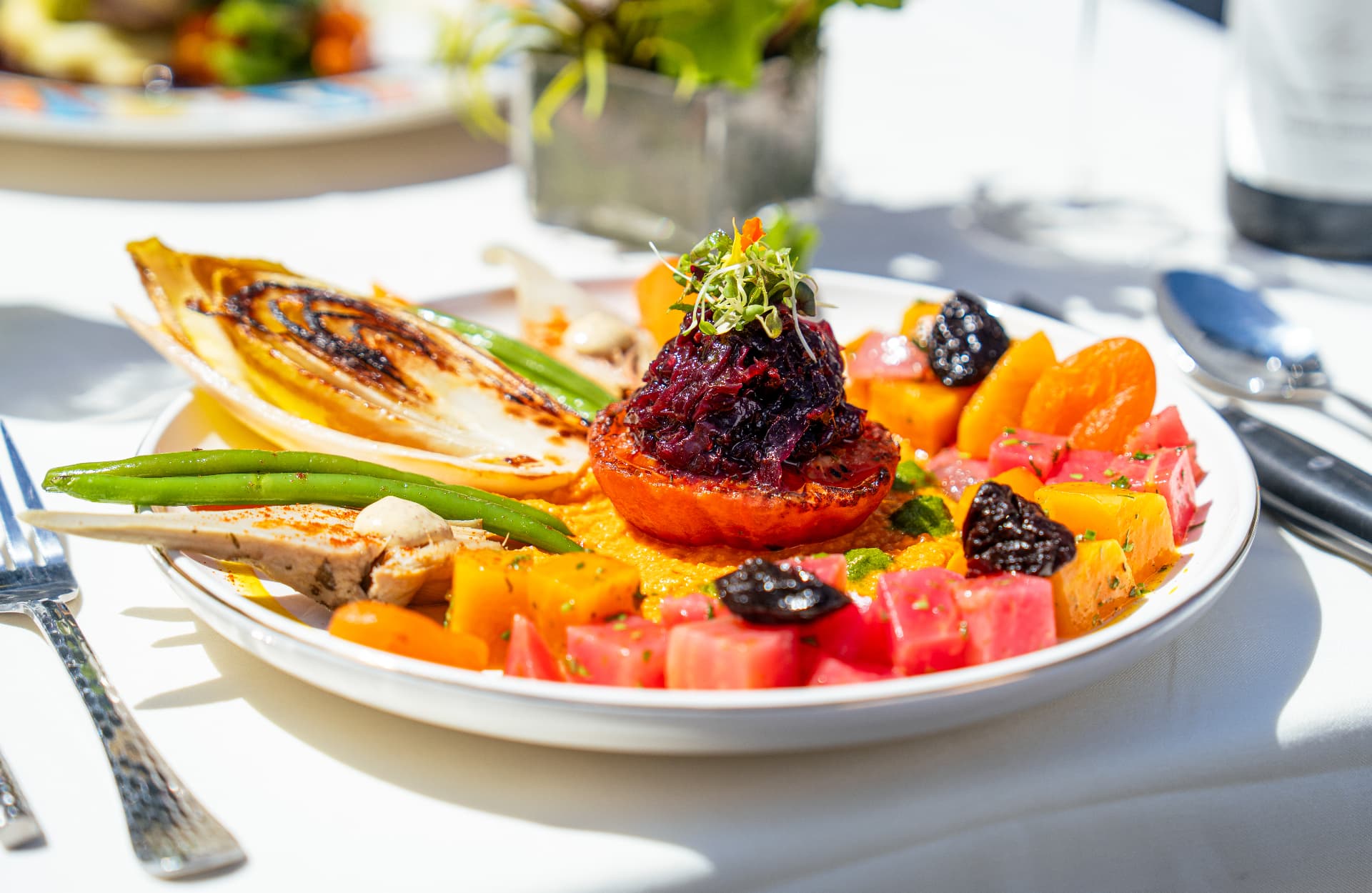 Roasted tomato topped with braised red cabbage alongside diced beets and green beans